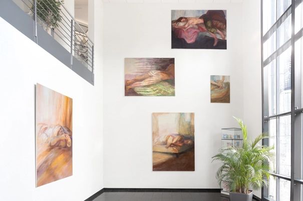Eine Bildkomposition an der großen Wand im Foyer der Firma Schaebens. Es hängen drei figurative Großformate und ein Mittelformat vor Kopf und seitlich eine gestische Aktmalerei in Orange gehalten.